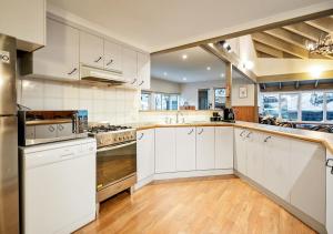 a kitchen with white cabinets and white appliances at Crystal Brook Lodge in Dinner Plain