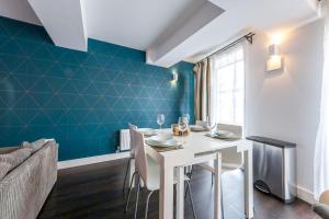 un comedor con una mesa blanca y una pared azul en The New52 Oxford by 360Stays - Bespoke 2 Bed Luxury Apartment in the Heart of Oxford City Center with Parking, en Oxford