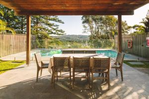 eine Terrasse mit Tisch und Stühlen und ein Swimmingpool in der Unterkunft Turimetta Beach House in Warriewood