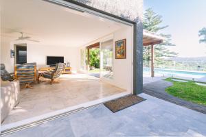 Eine Glasschiebetür führt in ein Wohnzimmer mit Terrasse. in der Unterkunft Turimetta Beach House in Warriewood