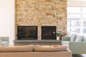 ein Wohnzimmer mit einem Steinkamin und einem TV in der Unterkunft Turimetta Beach House in Warriewood