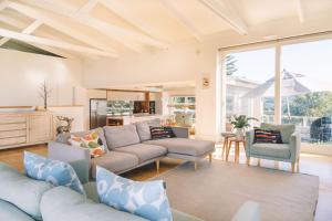 ein Wohnzimmer mit einem Sofa und Stühlen sowie eine Küche in der Unterkunft Turimetta Beach House in Warriewood