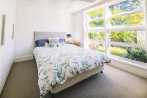 ein Schlafzimmer mit einem Bett und zwei Fenstern in der Unterkunft Turimetta Beach House in Warriewood + 23 Fotos