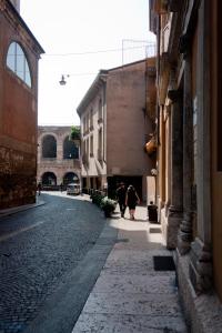 zwei Menschen, die eine Straße zwischen Gebäuden entlang gehen in der Unterkunft B&B Principe all'Arena in Verona