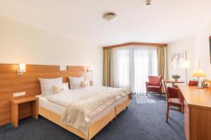 a hotel room with a large bed and a desk at acora Bochum Living the City - Apartments in Bochum