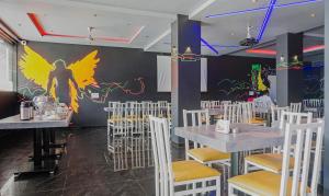 a restaurant with white tables and chairs and a painting on the wall at Treebo Trend The Utsav, Nashik in Nashik