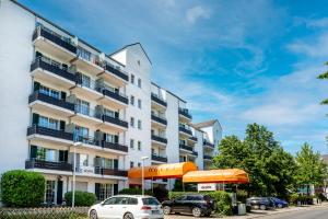 un edificio bianco con macchine parcheggiate di fronte di acora Düsseldorf Living the City a Dusseldorf