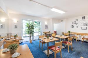 une salle à manger avec des tables, des chaises et des tables en bois dans l'établissement acora Düsseldorf Living the City - Apartments, à Düsseldorf