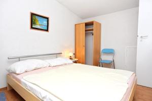 a bedroom with a bed and a blue chair at Apartments with a parking space Sabunike, Zadar - 5822 in Privlaka