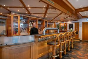 a woman standing behind a bar with stools at Hotel Elisenhof Mönchengladbach in Mönchengladbach