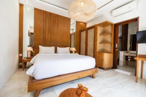 um quarto com uma grande cama branca e uma secretária em Tamantara em Ubud