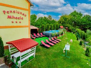 a resort with chairs and a pool in a yard at Pensiunea Mihaela in Novaci