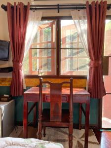 a wooden desk with a chair in front of a window at Chomklong Experience in Pak Chong