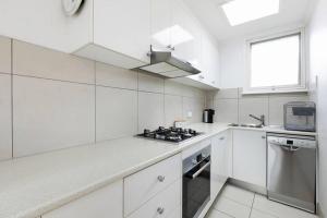 a white kitchen with a stove and a window at Belle Retreat by the River & Ocean Pet Friendly in Ocean Grove +7 photos