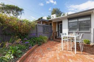 a patio with a table and chairs in front of a house at Belle Retreat by the River & Ocean Pet Friendly in Ocean Grove