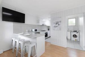 a white kitchen with a counter and stools at Belle Retreat by the River & Ocean Pet Friendly in Ocean Grove