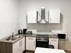 a kitchen with white cabinets and a sink at cosy three room apartment with flatscreen TV in Recklinghausen