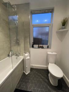 a bathroom with a toilet and a shower and a window at Stylish and Modern 3 bed Apartment with FREE PARKING, in Newcastle upon Tyne