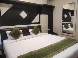 ein Schlafzimmer mit einem großen weißen Bett mit grünen Kissen in der Unterkunft Hotel Rudraksh- Near VIP Airport Guwahati in Guwahati