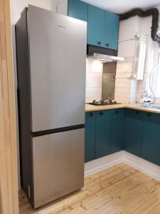 a stainless steel refrigerator in a kitchen with blue cabinets at STUDIO 22 in Craiova +6 photos