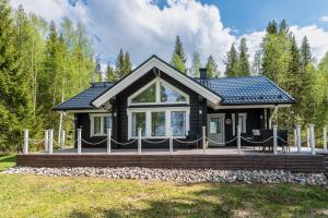 ein Blockhaus mit einer Veranda und einem Haus in der Unterkunft Lähderinne - Beachfront 2 bedroom log cabin, private beach & sauna in Puolanka