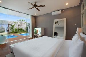 1 dormitorio con cama blanca y ventana grande en The Daha Luxury Villas, en Seminyak