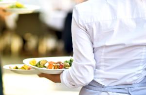a chef holding a plate of food on a table at Garner Hotel Oberhausen in Oberhausen