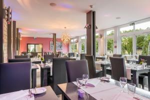un restaurante con mesas, sillas y ventanas en Select Hotel Oberhausen en Oberhausen