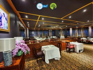 un restaurant avec des tables blanches, des chaises et des fleurs dans l'établissement Royal Phuket City Hotel - SHA Extra Plus, à Phuket
