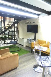 ein Wohnzimmer mit einem TV, einem Sofa und Stühlen in der Unterkunft Hotel Balbo in Turin