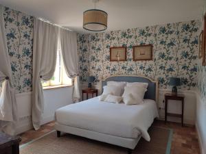 um quarto com uma cama com papel de parede floral azul em Manoir de Daubeuf em Daubeuf-Serville