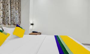 a white bed with colorful pillows on it at Itsy By Treebo - Heraa International in Mumbai