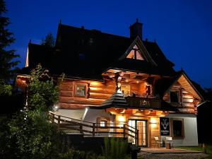 a wooden house with lights on the side of it at Villa Capra - Apartments Adult Only in Zakopane