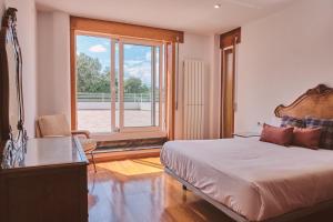 een slaapkamer met een bed, een bureau en een raam bij Casa Jacoba Pool House by Serendipia Turismo in Ortoño