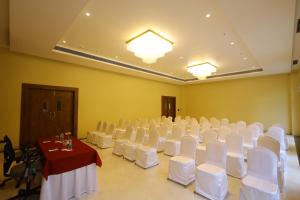 un salón de banquetes con sillas blancas y una mesa con mantel rojo en The Aurum Subrahmanya, en Subrahmanya