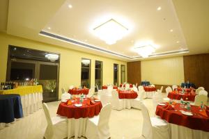 a banquet hall with tables and chairs with red and white tablecloths at The Aurum Subrahmanya in Subrahmanya