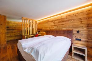 a bed in a room with a wooden wall at Hotel Steinbock in Livigno