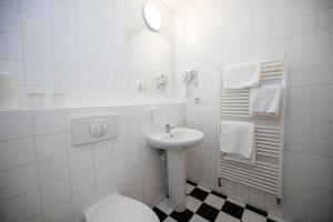 een witte badkamer met een wastafel en een toilet bij Hotel Praha in Broumov