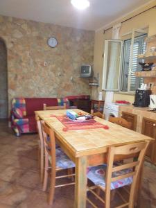 eine Küche mit einem Holztisch mit Stühlen und einer Uhr an der Wand in der Unterkunft Villetta Torre Salsa in Siculiana