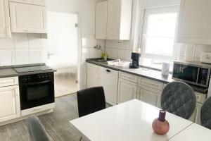 une cuisine avec des placards blancs et une table avec des chaises dans l'établissement 3 bedroom apartment in Leverkusen, à Leverkusen