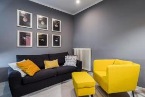 - un salon avec un canapé noir et un fauteuil jaune dans l'établissement Harinero, characteristic apartment in the center, à SantʼAgata Bolognese