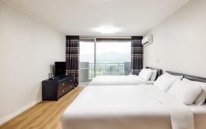 two beds in a room with a large window at Kensington Resort Gyeongju in Gyeongju