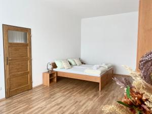 a white room with a bed and a wooden floor at Penzion Kundratice in Kundratice