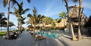 a resort swimming pool with chaise lounges and palm trees at Arennas Mancora in Máncora