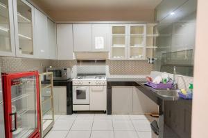 una cocina con armarios blancos y electrodomésticos blancos en RedDoorz Premium near RS Pondok Indah La Maison en Yakarta