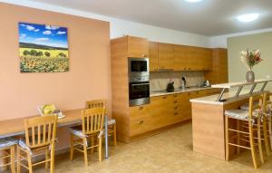 una cocina con armarios de madera y una barra con sillas en Penzion Kundratice, en Kundratice