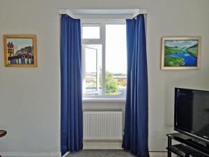una ventana con cortinas azules en la sala de estar en Bealadangan Holiday Home 