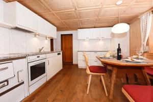 a kitchen with white cabinets and a wooden table at Veronikas Chalet in Sankt Gallenkirch