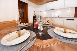 - une table à manger avec 2 assiettes blanches et des verres à vin dans l'établissement Veronikas Chalet, à Sankt Gallenkirch