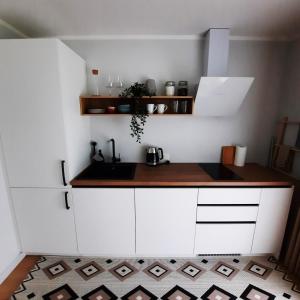 cocina con armarios blancos y encimera en Kesterciems seaside apartment with terrace, en Ķesterciems